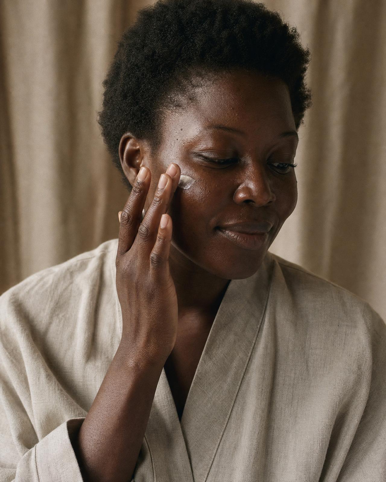 Femme appliquant son soin visage, lumière naturelle